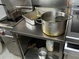 stainless steel counter top with pots and pans on it in a commercial kitchen