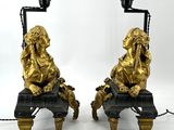 two golden statues of lions sitting on a bench