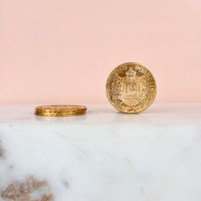 une pièce d'or posée sur un comptoir en marbre, près d'un mur rose