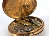 a gold pocket watch sitting on top of a white table