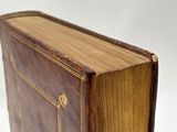 an old brown book sitting on top of a white surface