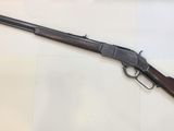 a rifle with a wooden barrel and a wooden handle on a white surface