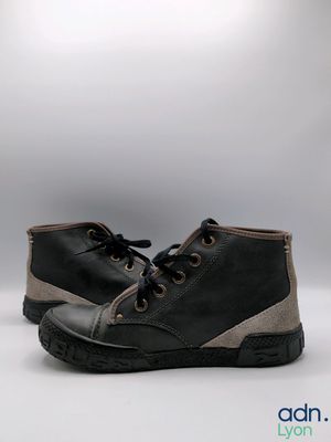 pair of black and grey shoes on a white surface with a light in the background