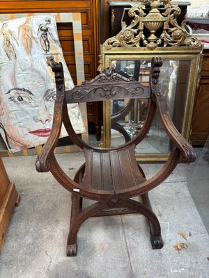 une chaise en bois ornée d'une peinture, placée devant un miroir