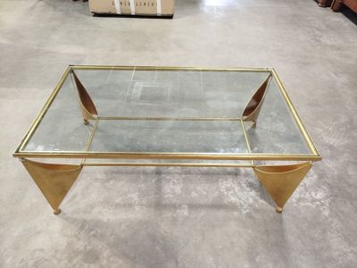une table basse en verre avec des pieds dorés et un plateau en verre