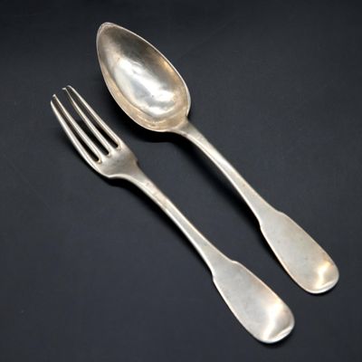 two silver spoons and a fork on a black surface