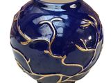a blue vase with gold designs on it on a white background