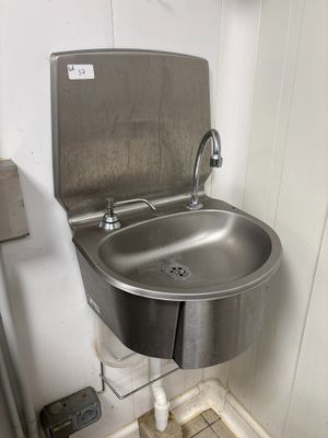 a stainless steel sink in the corner of a bathroom