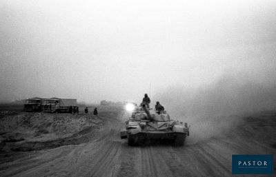 black and white photo of a tank driving down a dirt road
