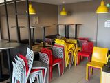des chaises et des tables aux couleurs vives dans un restaurant au sol à carreaux