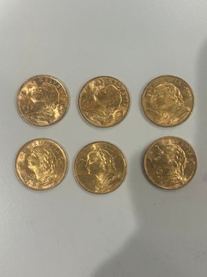 six souverains d'or posés sur une table, à côté d'une bouteille de vin