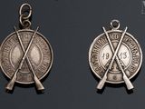 two silver medals with crossed swords on them on a black background