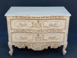 une commode blanche dont les tiroirs sont ornés de sculptures élaborées