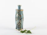 a small blue vase with a leaf on the ground