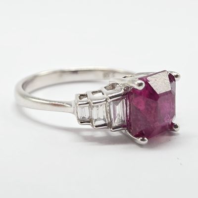 un gros plan d'une bague sertie d'un rubis et de diamants sur fond blanc