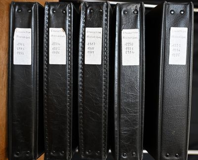 Plusieurs classeurs noirs sont alignés sur une étagère