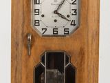 une horloge en bois posée sur une table, avec un mur blanc en arrière-plan