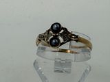 a gold ring with two black pearls on it