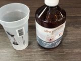 une bouteille de liquide et une tasse posées sur une table