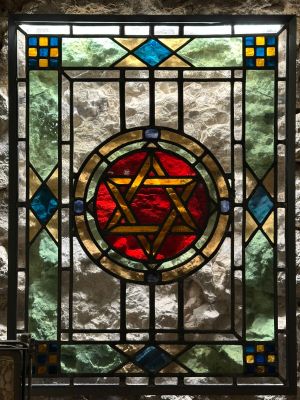 a close up of a stained glass window with a star of david on it