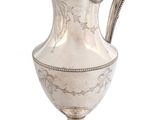 an antique silver pitcher with a handle on a white background