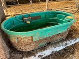un bac vert rempli d'eau posé dans une grange