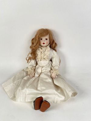 a doll that is sitting on the floor with a white dress