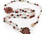 a close up of a necklace with pearls and red and black beads