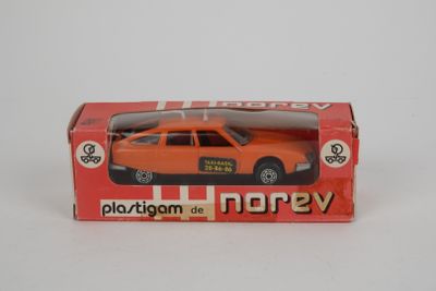 une petite voiture orange dans une boîte posée sur une surface blanche