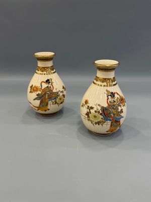 pair of chinese vases with figures on them sitting on a table