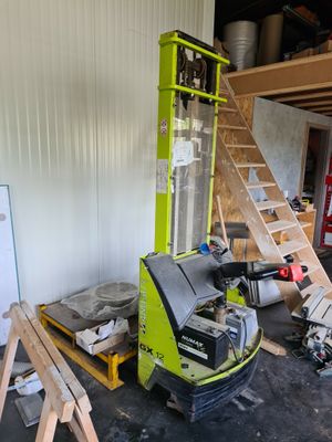 une photo d'un chariot élévateur dans un garage, avec une échelle