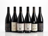 six bouteilles de vin sont alignées sur une surface blanche