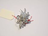 a silver and red brooch with a price tag on it