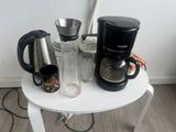 une petite table sur laquelle se trouvent une cafetière, une tasse et un mug