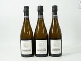 trois bouteilles de vin posées les unes à côté des autres sur une surface blanche