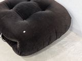 a black cushion on the floor next to a white wall