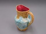 un vase bleu et jaune avec une anse rouge sur un fond gris