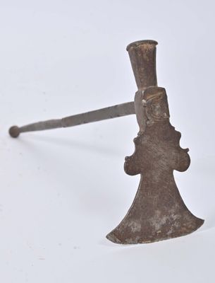 une vieille hache rouillée avec un manche en bois posée sur une surface blanche