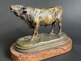 bronze statue of a bull on a marble base on a black background