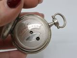 a person holding a silver pocket watch in their hand