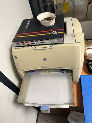 a printer sitting on top of a desk with a bowl of coffee on top of it