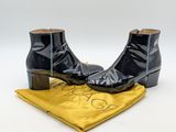 une paire de bottines en cuir noir posées sur un tissu jaune