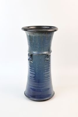 un vase bleu posé sur une surface blanche