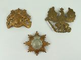 three gold brooches of various shapes and sizes on a white surface
