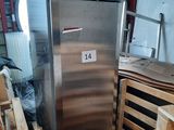 a silver refrigerator sitting in a warehouse with pallets of wood