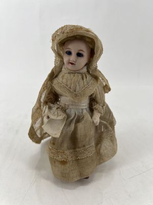une petite poupée qui porte une robe et un chapeau