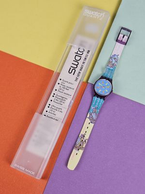 a watch sitting next to a tube of toothpaste on a colorful surface