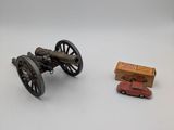 a toy car and a toy cannon on a white surface