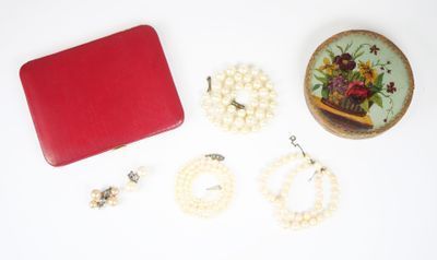 une boîte rouge contenant des perles et d'autres bijoux, posée sur un fond blanc