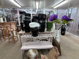 tables and chairs in a room with a lot of plants and vases